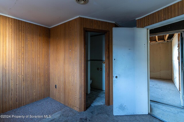 interior space with ornamental molding and wood walls