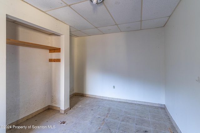 unfurnished bedroom with a paneled ceiling and a closet