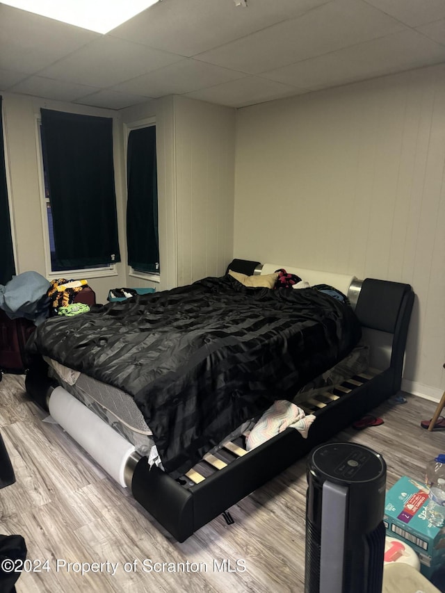 bedroom featuring light wood-type flooring and a drop ceiling