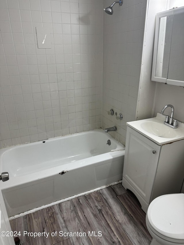 full bathroom featuring toilet, vanity, tiled shower / bath combo, and hardwood / wood-style flooring