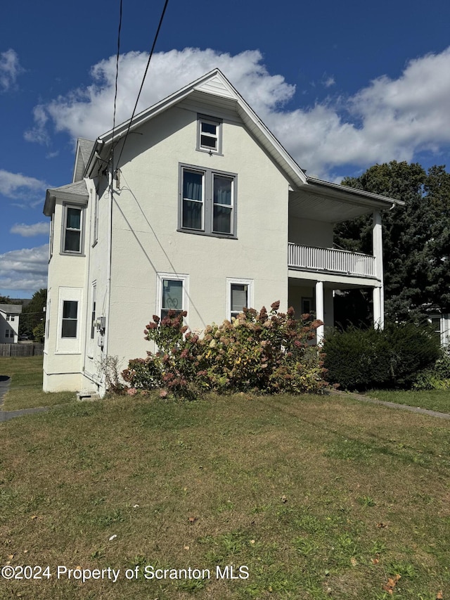 view of property exterior featuring a balcony and a lawn