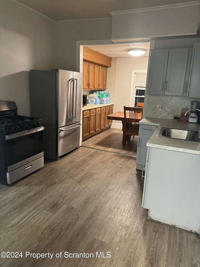 kitchen with sink, stainless steel appliances, backsplash, gray cabinets, and hardwood / wood-style flooring