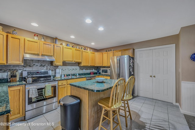 8 Parkland Dr Bldg 9, South Abington Twp, PA 18411 - kitchen with appliances with stainless steel finishes, dark countertops, light tile patterned floors, a kitchen island, and a wainscoted wall