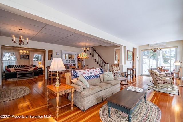 living area featuring a paneled ceiling, a notable chandelier, hardwood / wood-style floors, and stairs