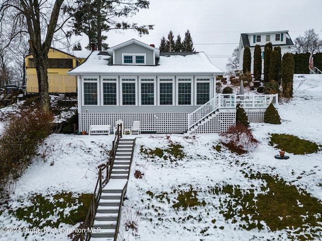 snow covered back of property featuring stairway