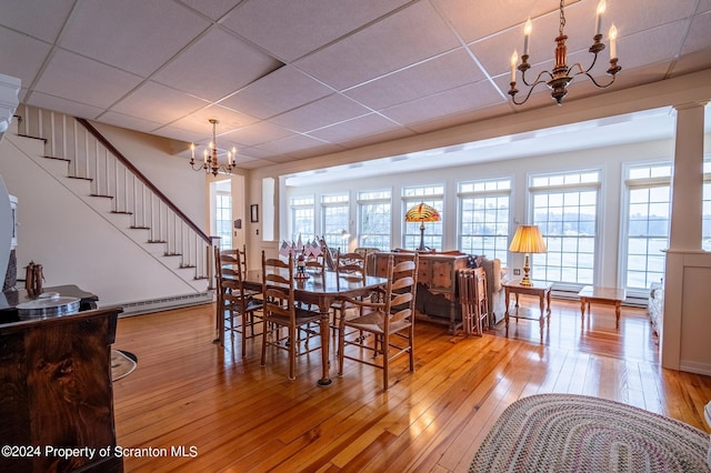 dining space featuring hardwood / wood-style floors, a notable chandelier, and a drop ceiling