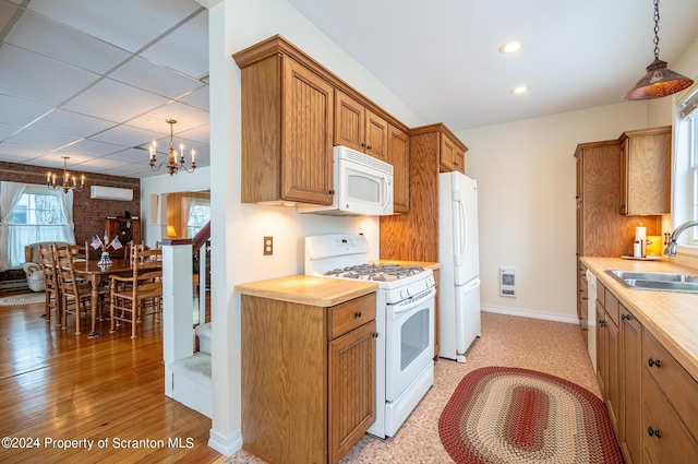 kitchen featuring baseboards, an inviting chandelier, hanging light fixtures, white appliances, and a sink