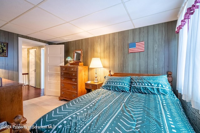 bedroom featuring wooden walls and a paneled ceiling