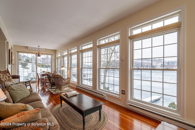 living area featuring a chandelier, a baseboard heating unit, and wood finished floors