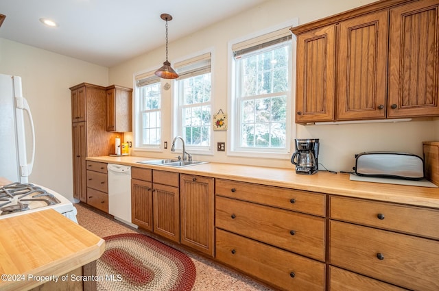 kitchen featuring white appliances, light countertops, brown cabinets, and a sink