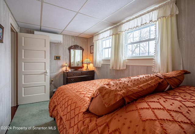 bedroom featuring wooden walls, a paneled ceiling, carpet floors, and a wall mounted AC