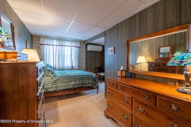 bedroom featuring a paneled ceiling, wooden walls, an AC wall unit, and carpet flooring