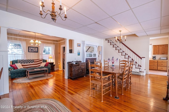 dining space featuring a notable chandelier, stairway, a paneled ceiling, and light wood-style floors