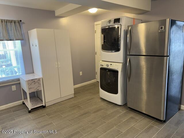 laundry room with stacked washer and clothes dryer, baseboards, laundry area, and wood tiled floor