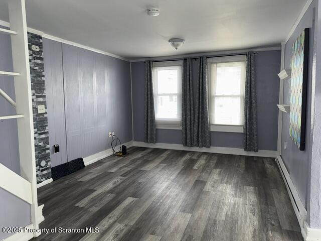 empty room with a baseboard radiator, baseboards, and wood finished floors