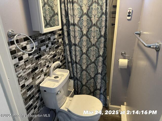 full bath featuring tile walls, toilet, and curtained shower