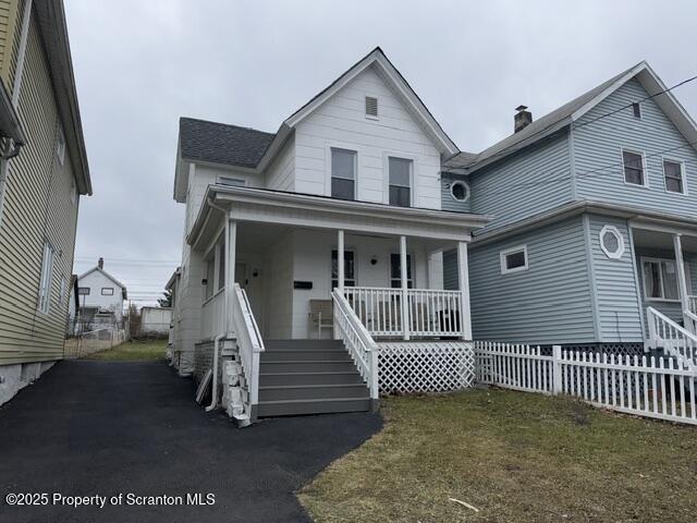 view of front of home featuring covered porch, fence, and a chimney