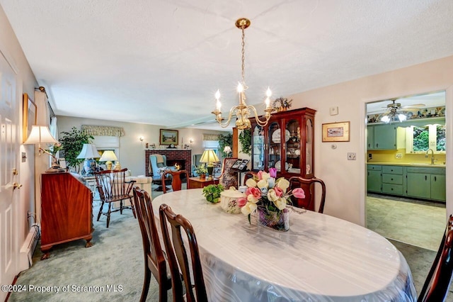 carpeted dining space featuring a textured ceiling, sink, ceiling fan with notable chandelier, and baseboard heating