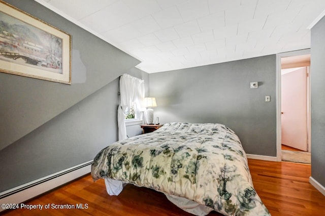 bedroom with hardwood / wood-style floors and a baseboard heating unit