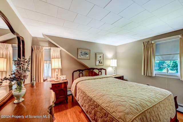 bedroom featuring hardwood / wood-style flooring and a baseboard heating unit