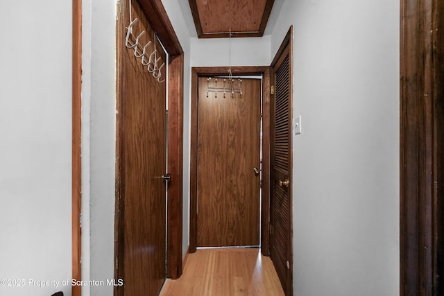 corridor featuring light wood finished floors and attic access