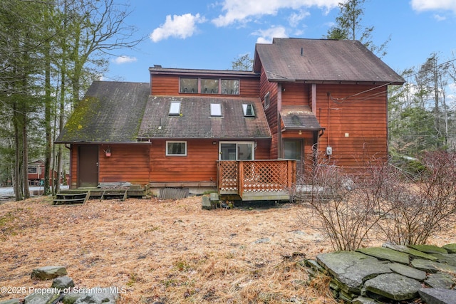 back of house featuring a shingled roof and a deck