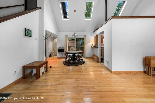 interior space featuring heating unit, a skylight, a towering ceiling, and light wood finished floors