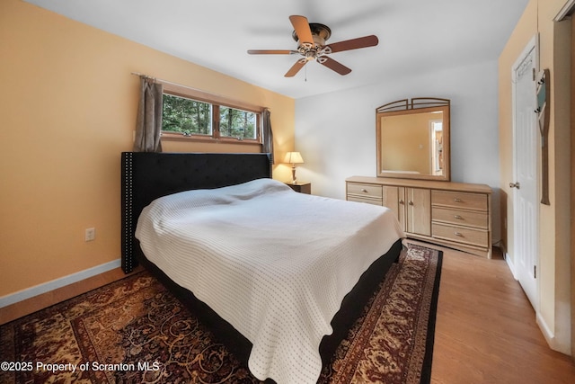 bedroom with a ceiling fan, light wood-style flooring, and baseboards