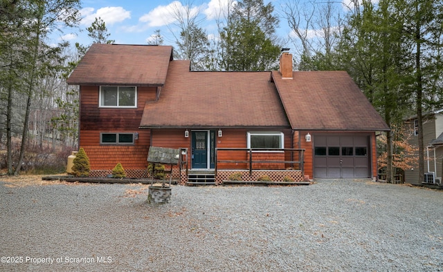 rustic home with a garage, gravel driveway, a tile roof, and a chimney