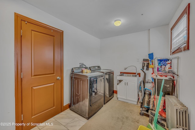 laundry area featuring sink, radiator heating unit, washing machine and dryer, and cabinets