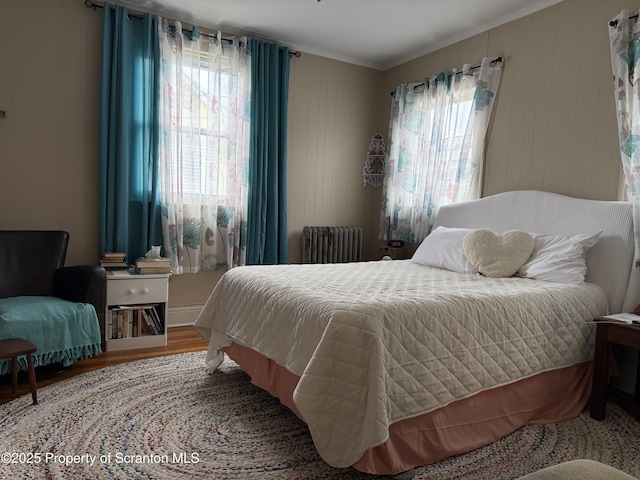 bedroom with radiator, wood finished floors, and crown molding