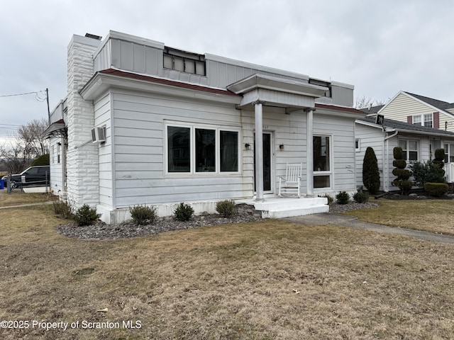 view of front of house with a front lawn, a wall unit AC, and board and batten siding