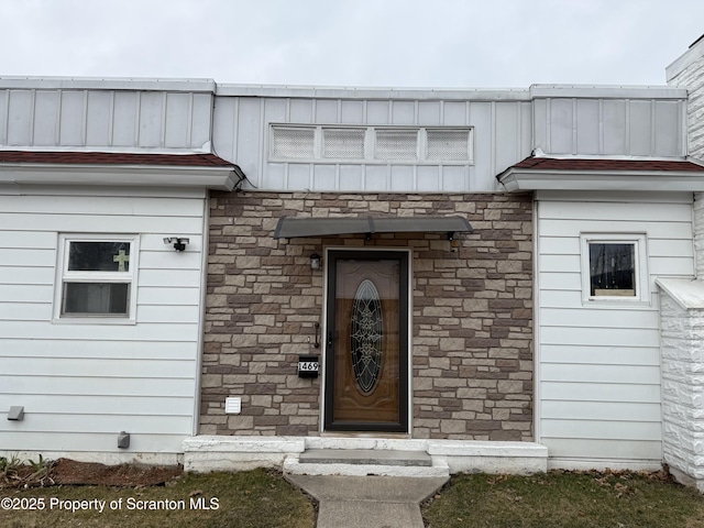 view of exterior entry with stone siding and board and batten siding