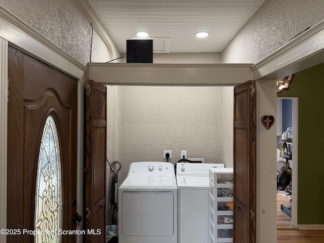 clothes washing area featuring a textured wall, independent washer and dryer, laundry area, and light wood finished floors