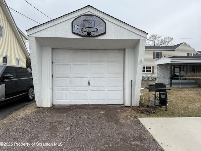 detached garage featuring driveway and fence