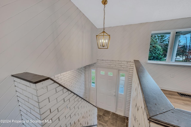 entryway featuring wooden walls, plenty of natural light, and a chandelier