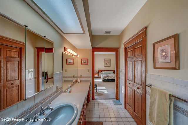 bathroom featuring tile patterned floors, tile walls, visible vents, and vanity