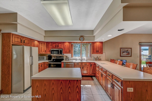 kitchen featuring light countertops, a peninsula, light tile patterned floors, and stainless steel appliances