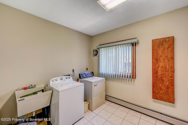 washroom featuring laundry area, washing machine and clothes dryer, a sink, a baseboard heating unit, and light tile patterned flooring