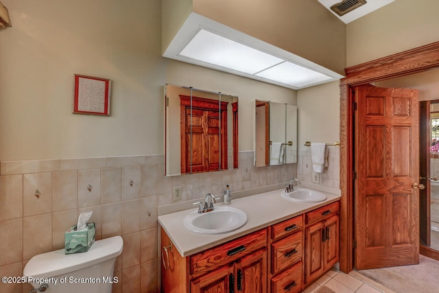 bathroom with visible vents, a sink, double vanity, and toilet