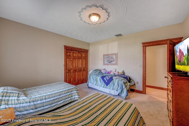 bedroom with visible vents, baseboards, a closet, and light carpet