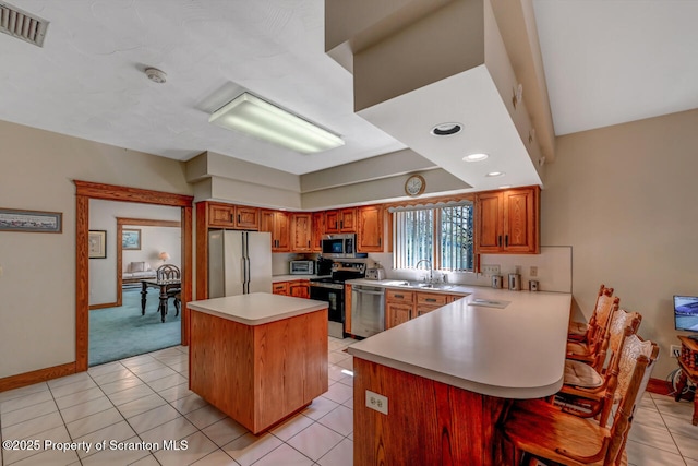 kitchen featuring appliances with stainless steel finishes, light countertops, a peninsula, baseboards, and visible vents