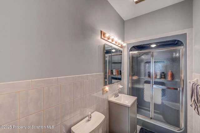 full bath with vanity, tile walls, a stall shower, and toilet