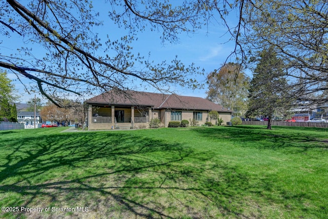 rear view of property with fence, covered porch, and a lawn
