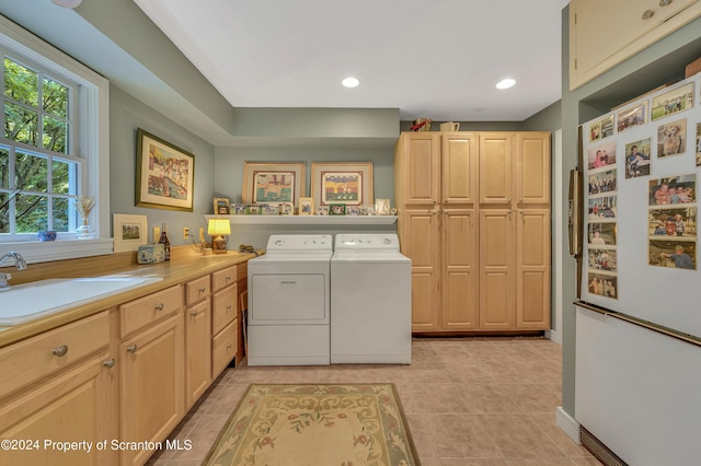 clothes washing area with separate washer and dryer, sink, light tile patterned floors, and cabinets