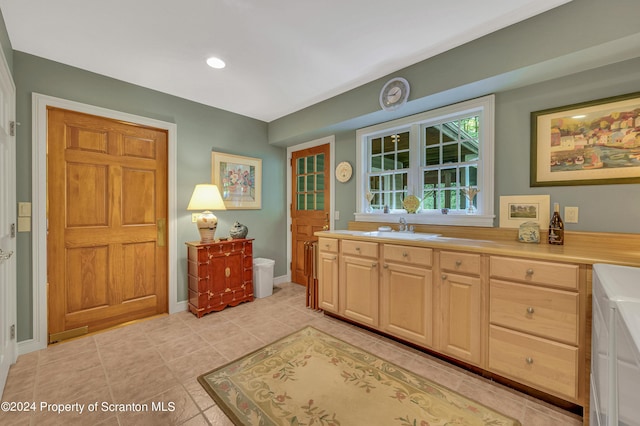 kitchen featuring light tile patterned flooring, light brown cabinetry, and sink