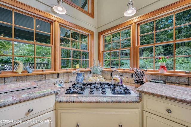 kitchen featuring cream cabinetry, light stone countertops, tasteful backsplash, and stainless steel gas stovetop