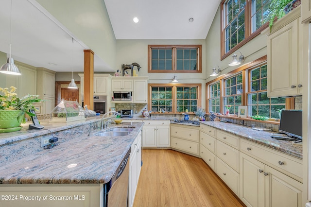 kitchen featuring pendant lighting, sink, cream cabinetry, and stainless steel appliances