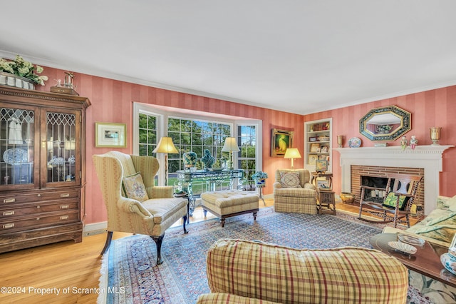 living room featuring crown molding, a fireplace, and light hardwood / wood-style flooring