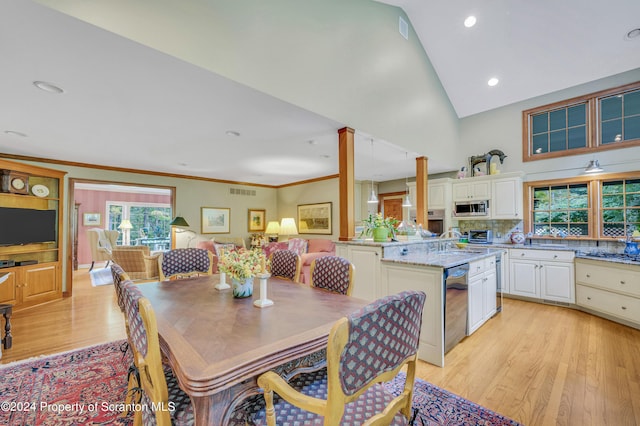 dining space with light hardwood / wood-style floors, crown molding, sink, and high vaulted ceiling